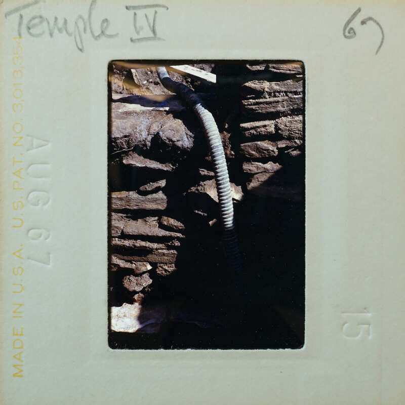 Detail of a stone wall with a modern hose running through it.