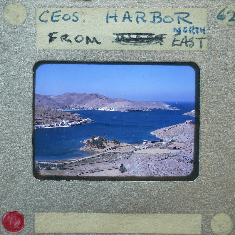 A vintage photograph of a harbor with mountains in the background, enclosed within an old film strip frame.