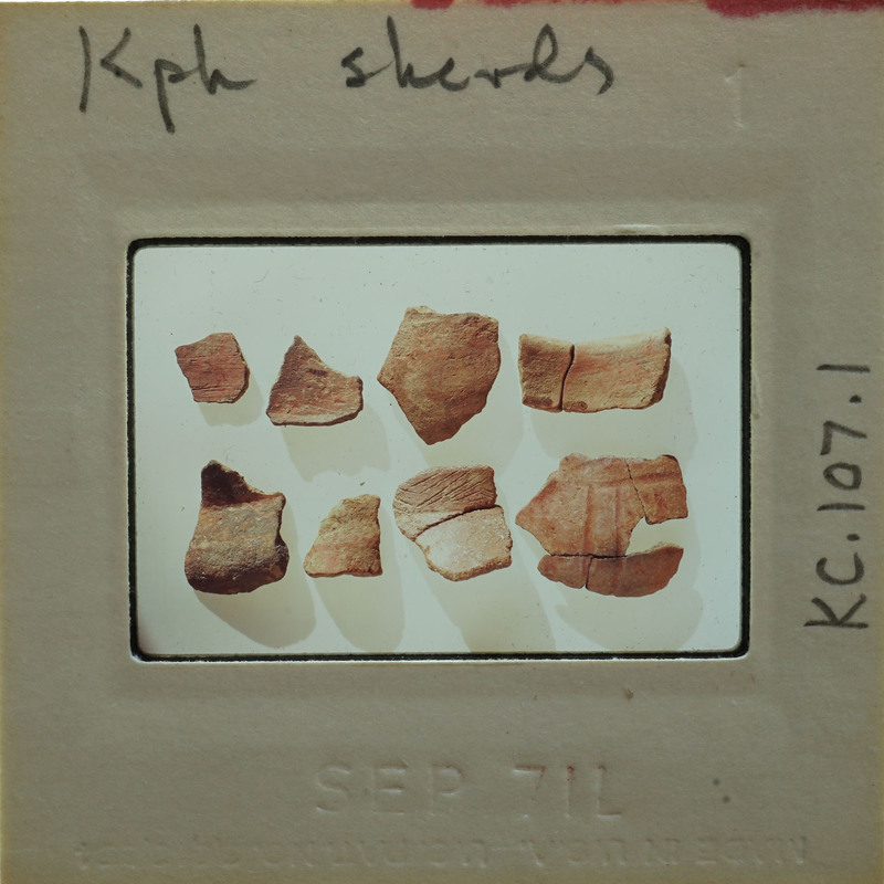 A collection of broken pottery pieces on a white surface, with a label indicating they are from ancient times.