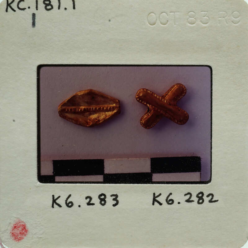Two small gold-colored objects on a white surface with measurements and labels.