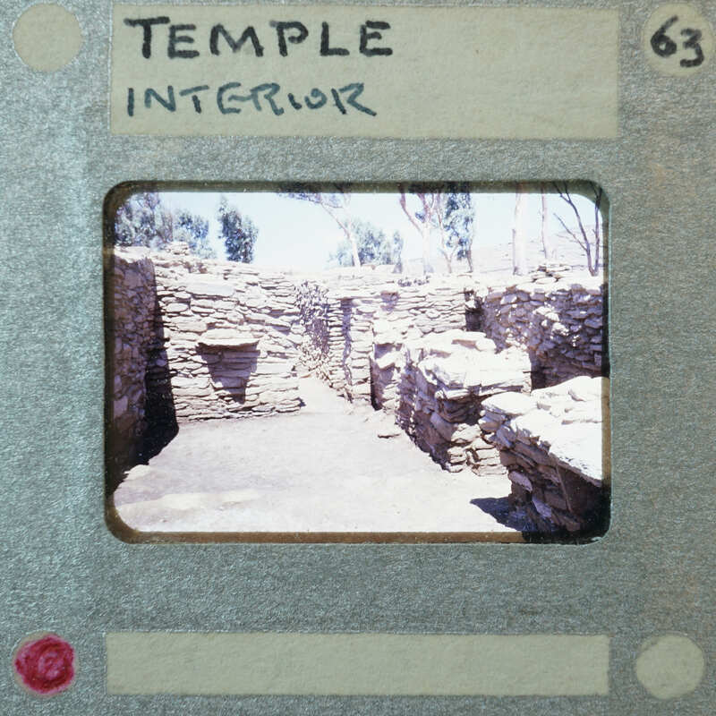 Stone building, possibly a temple interior, with visible ruins and a doorway leading to another room.