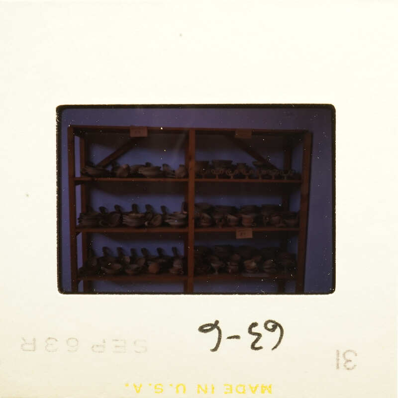 Shelves filled with various objects, possibly antiques or collectibles, on a film strip labeled "G-29".