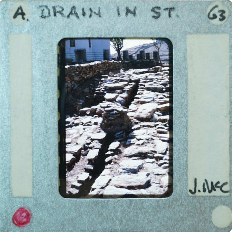 A photograph of a stone drainage ditch with a film strip border.