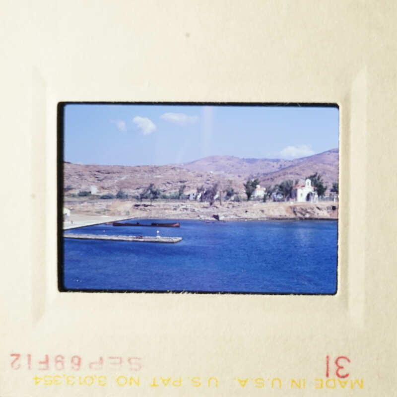 A scenic view of a beach and ocean with boats, captured on an old photo slide.