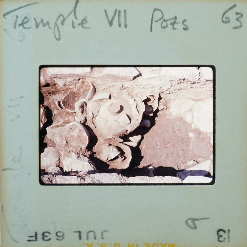 Pottery in situ on surface in stone walled room.