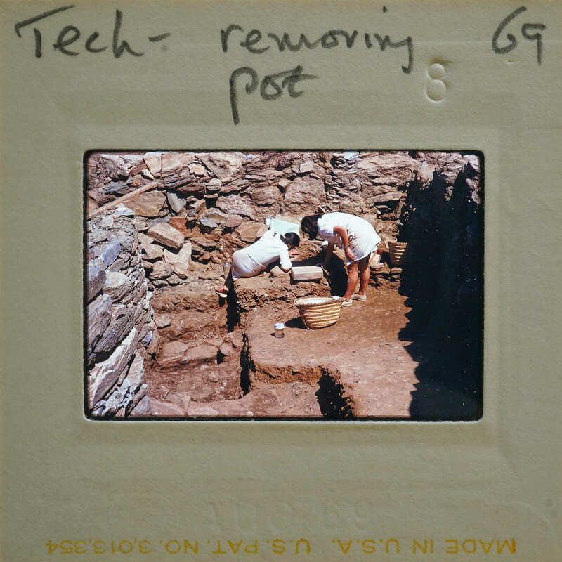 Two people working on a stone wall with hand tools.