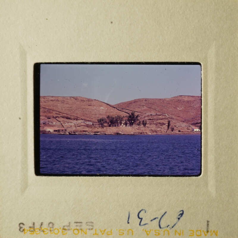 A tranquil view of a serene lake with hills and a clear sky.