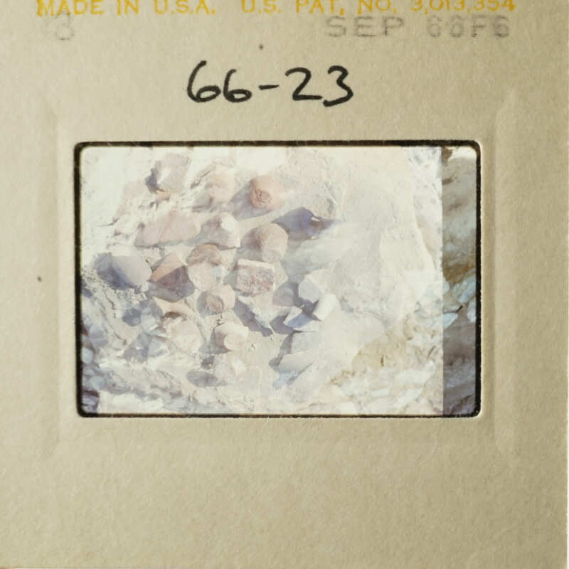 The image shows a vintage photograph with a label and a barcode, depicting a rocky landscape with a close-up of rocks and stones.
