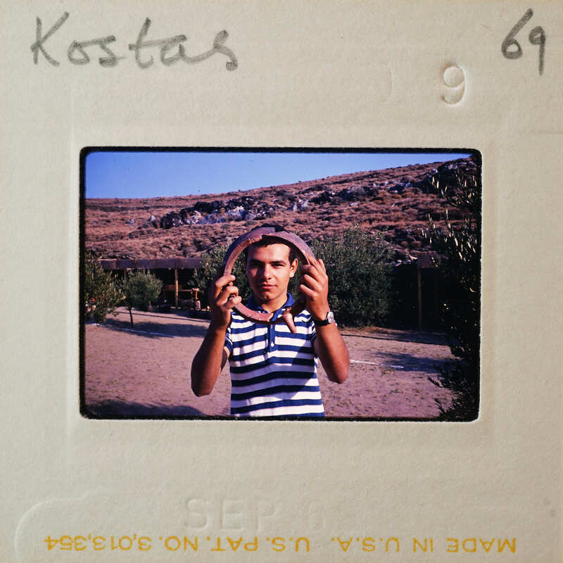 A man holding a large round pot rim, with a mountainous landscape in the background.