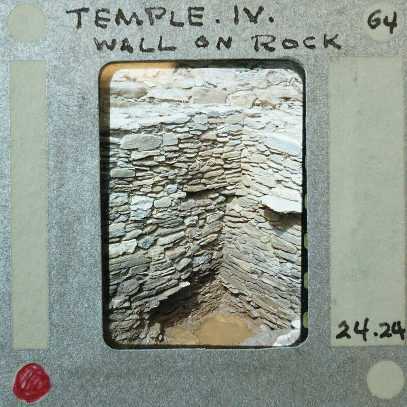 Tall stone wall corner with mud on the floor.