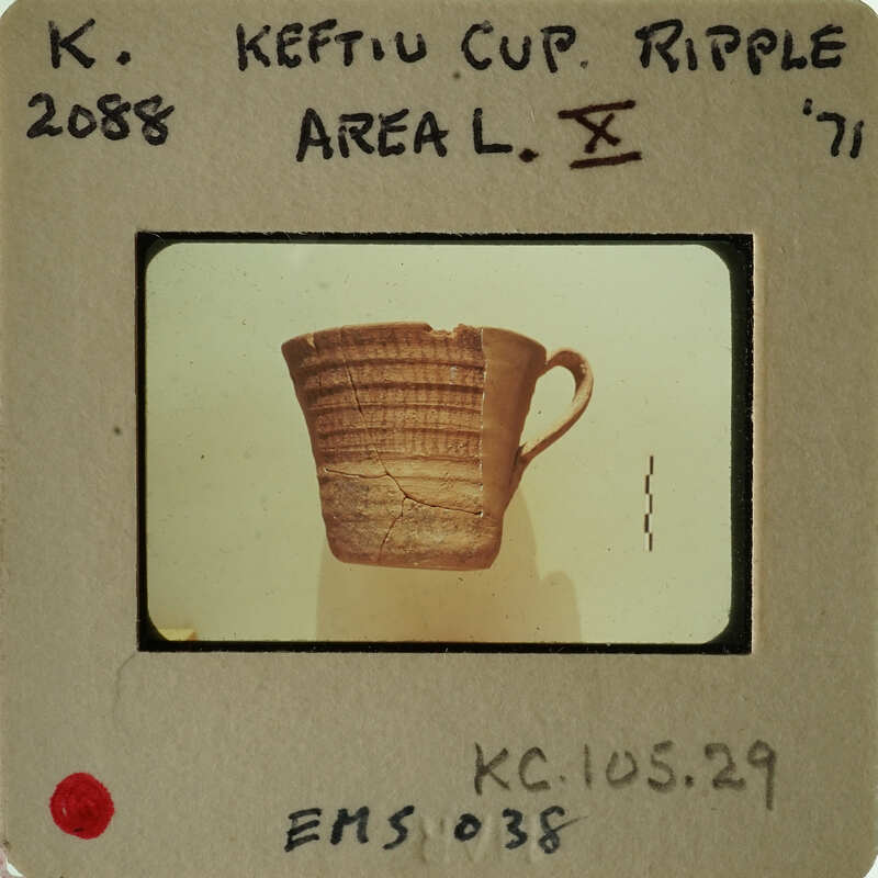 Old ceramic mug with handle, photographed on a white background and displayed on an identification card.