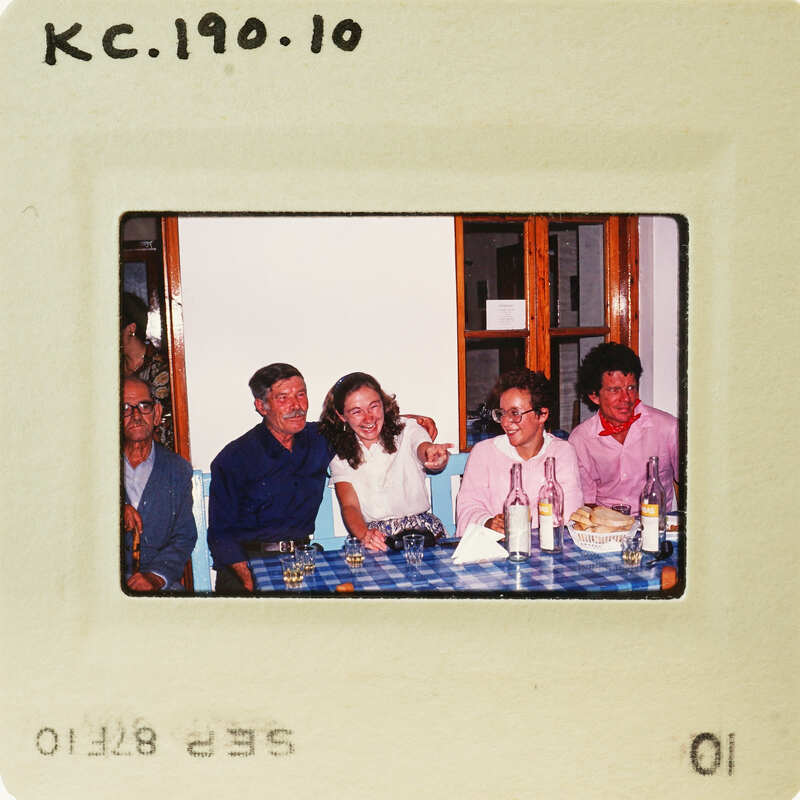 A vintage photo of people gathered around a table with food and drinks. Catalog number KC.190.10