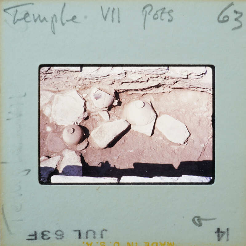 Pottery in situ on surface in stone walled room.