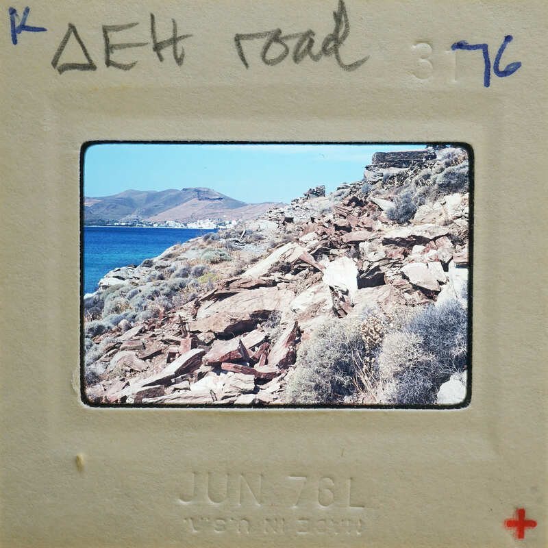 A vintage photo of a rocky coastline with the sea and mountains in the background, framed by an old Polaroid-style border with handwritten notes.