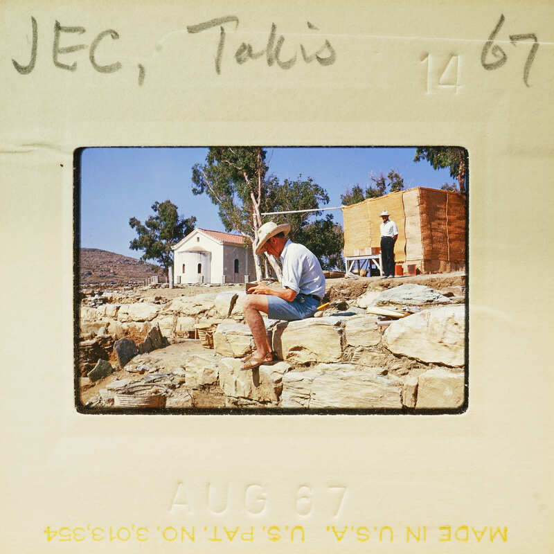 Man sitting on rocks, reading a book.