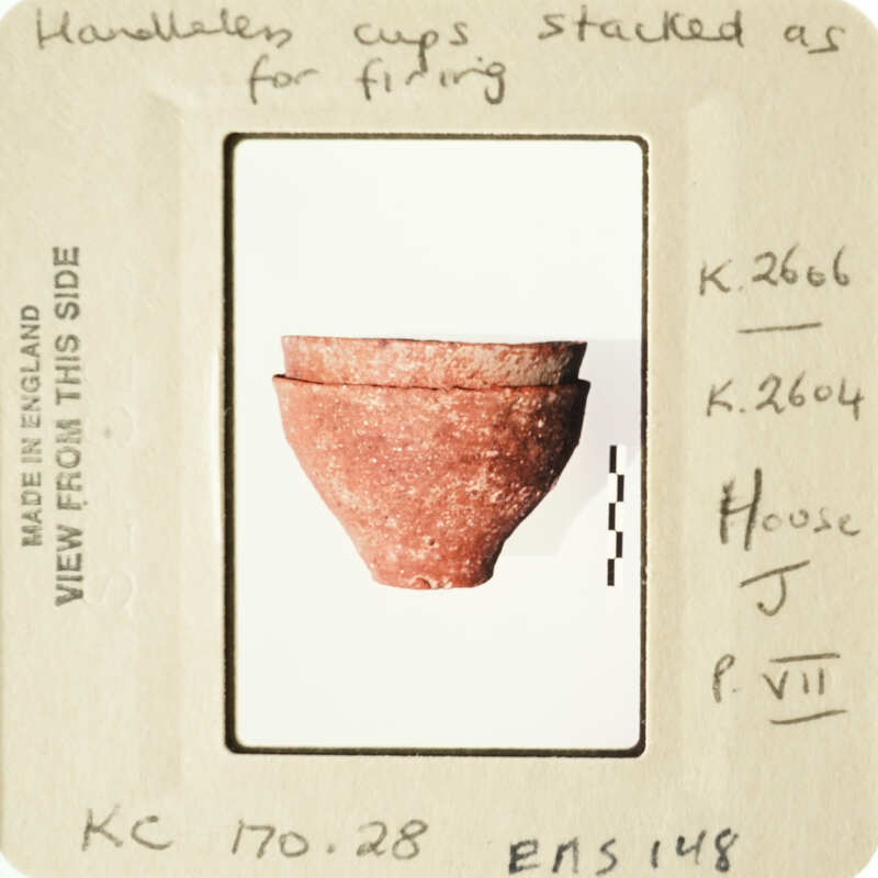 Ancient clay pot with red and brown hues, displayed on a light background.
