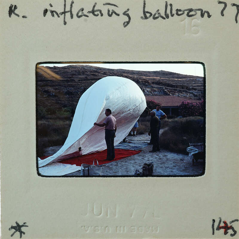 Man working on large white balloon outdoors.