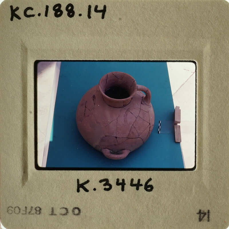 Ancient clay pot with visible cracks and imperfections, displayed on a surface.