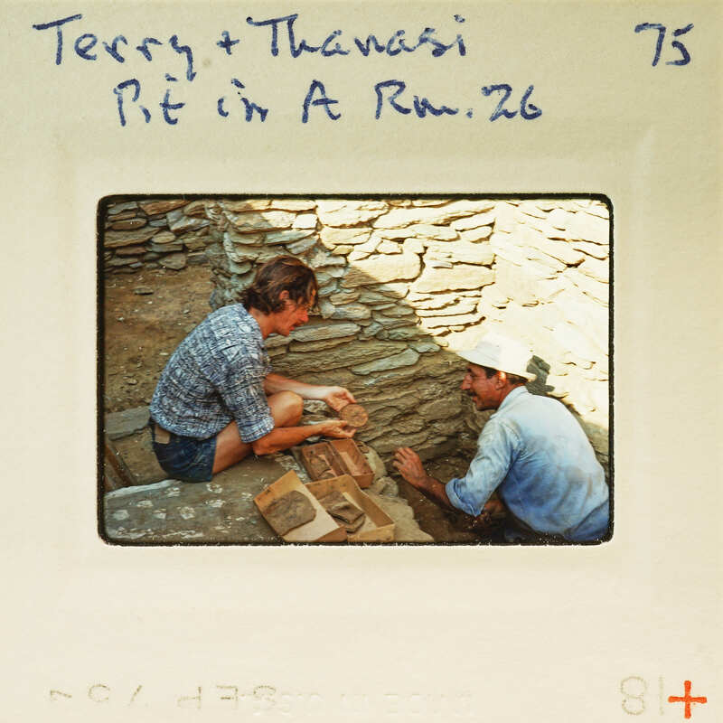 Two people working on a stone wall with bricks and mortar.