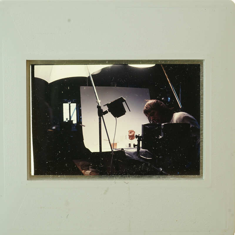 A man operating a camera on a set with lighting equipment.