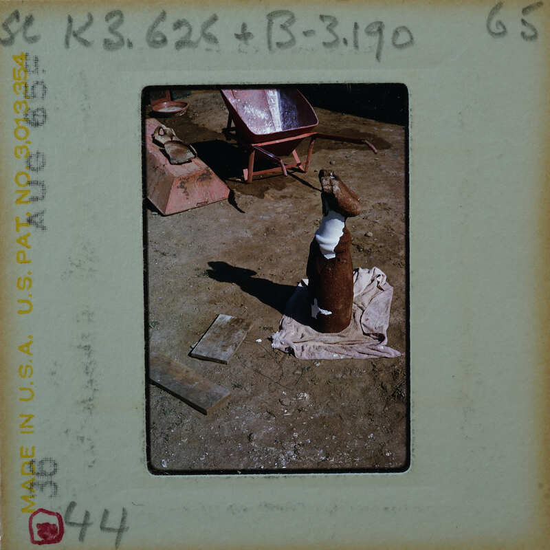 A photograph of a work area with various tools and materials, including a large pipe on the ground.