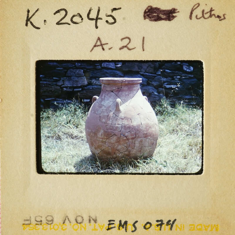 Large clay pot with cracks and chips, sitting on grass.