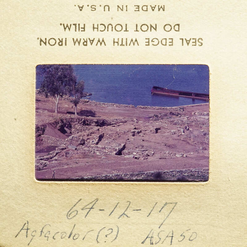 A photograph showing an outdoor scene with water and land features, possibly ruins, with handwritten notes on the bottom right corner.