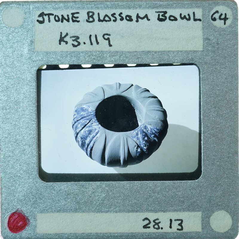 A photograph of a small stone bowl with diagonal incised lines from the top.