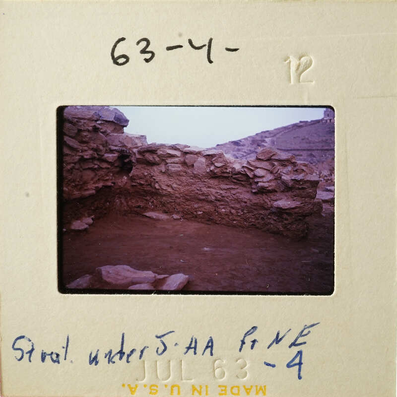 A photograph of an ancient stone structure with a view of mountains in the background.