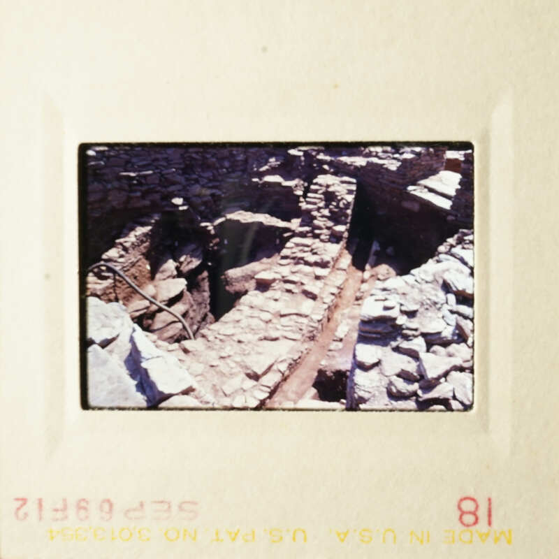 The photograph shows an ancient stone structure, possibly a tunnel or cave, with visible rock walls and a narrow passageway.
