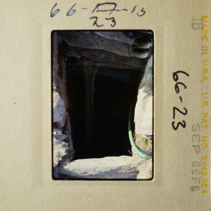 The photo shows an underground tunnel with pipes and water inside, taken from above.