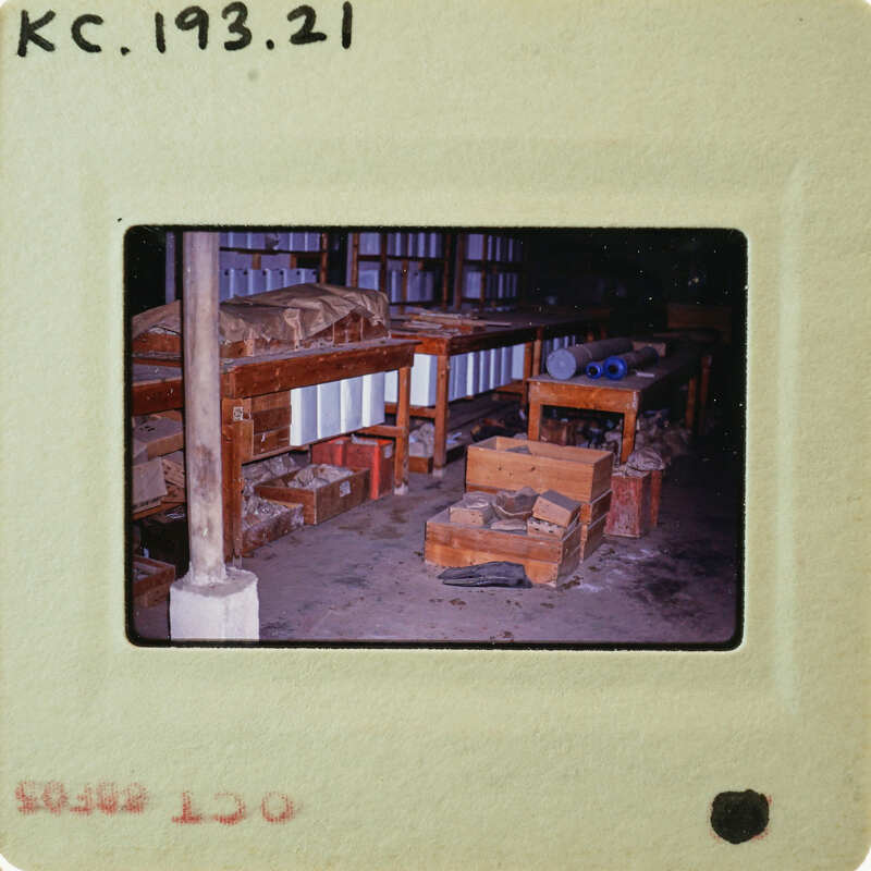 A photograph of a cluttered workshop with wooden benches and various items on shelves.