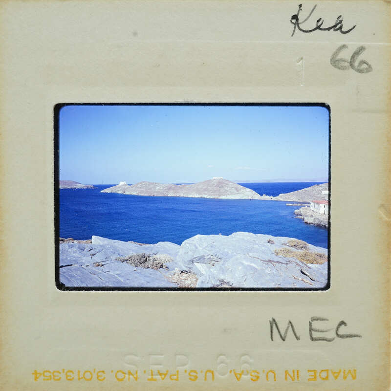 Picture of a rocky coastline with an island and blue water, taken from a vintage Polaroid photo.