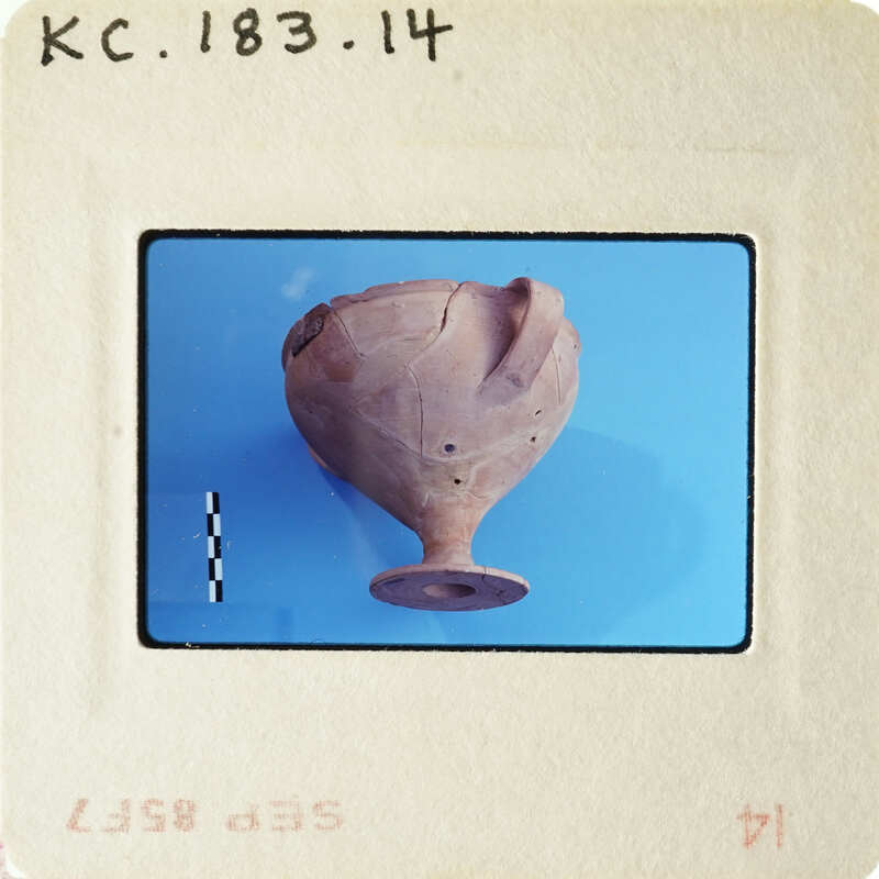 Ancient pottery artifact with visible wear and tear, photographed on a blue background.