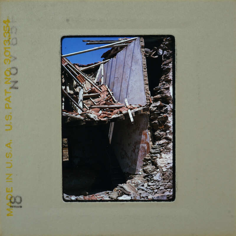 Damaged building with exposed interior and debris on ground.