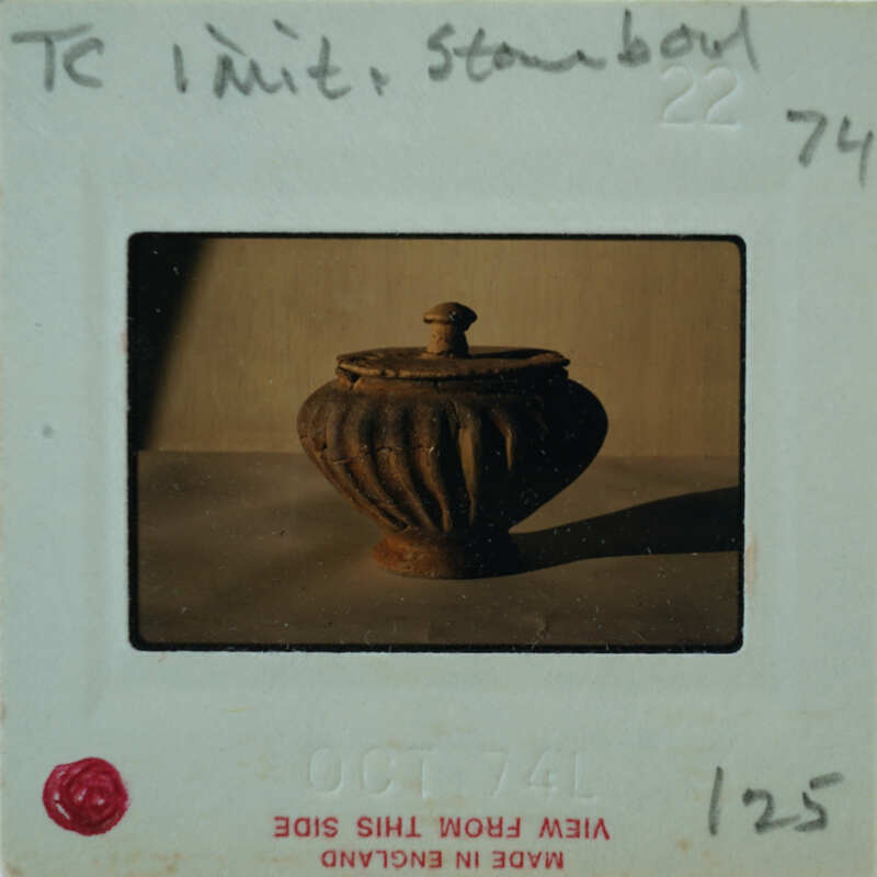 A photograph of an old, weathered metal container with a lid.