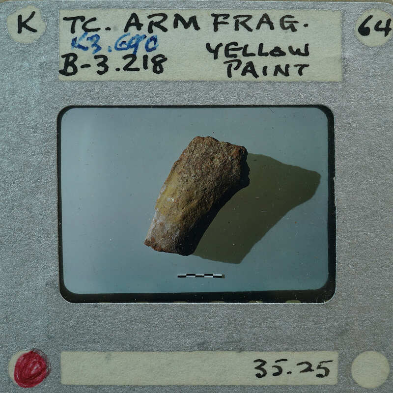 A small yellow rock on a white surface with a label and barcode.