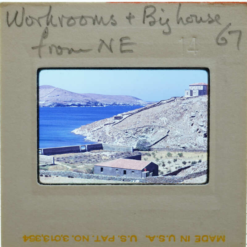 A slide of a coastal landscape with blue water, mountains, and buildings.