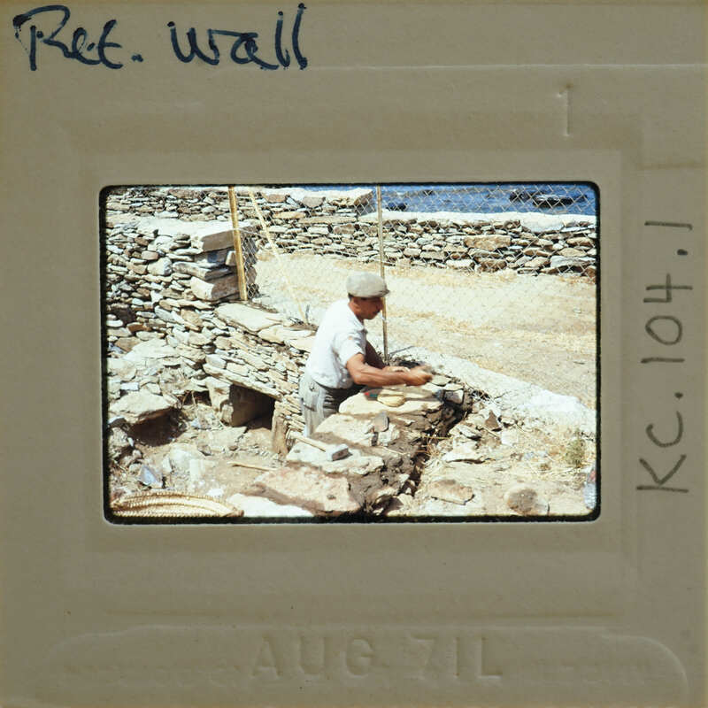 A man working on a stone wall with various tools and materials around him.