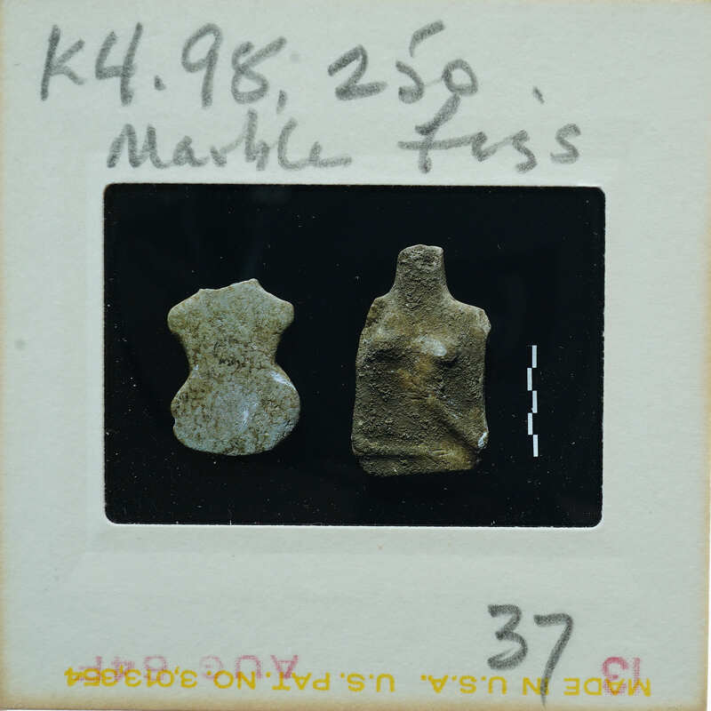 A small clay figurine of a humanoid shape on display with a price tag and description.