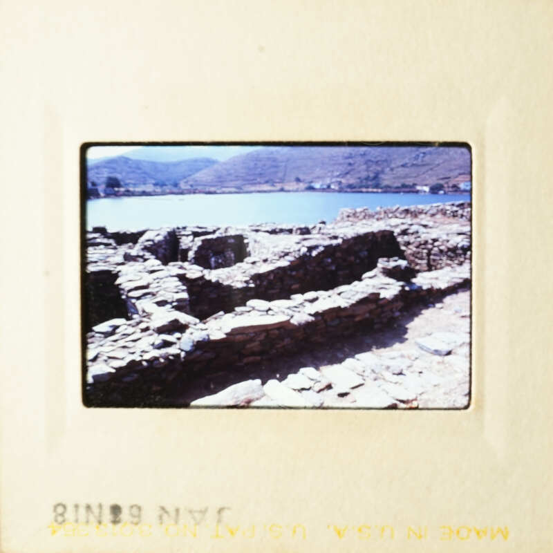 This is an image of a stone structure, possibly ruins, near a body of water with a clear sky above.