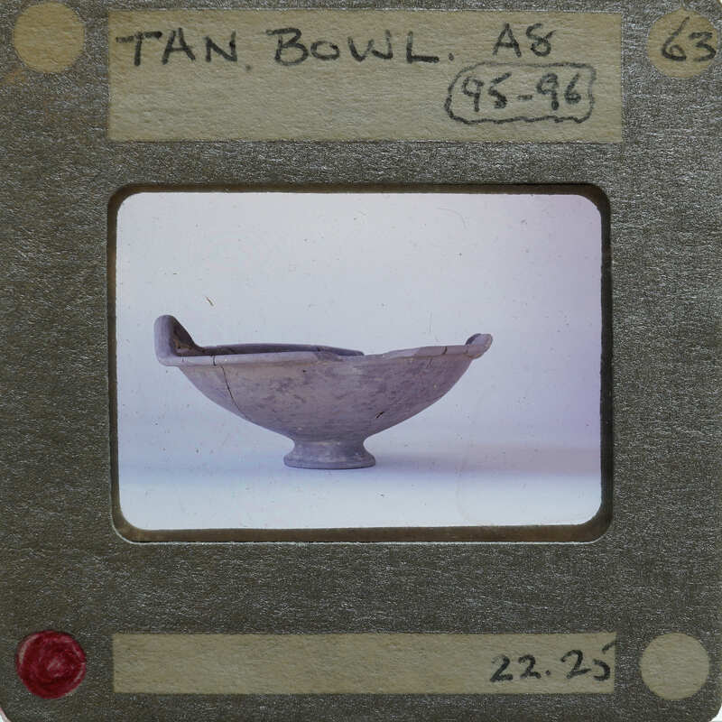 Bowl with one handle visible in profile on surface.