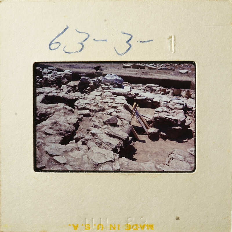 Ancient ruins with stone walls and dirt ground, possibly from an archaeological site.