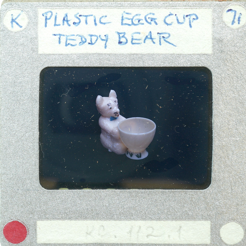 A small plastic bear figurine holding a cup of coffee on a film strip.
