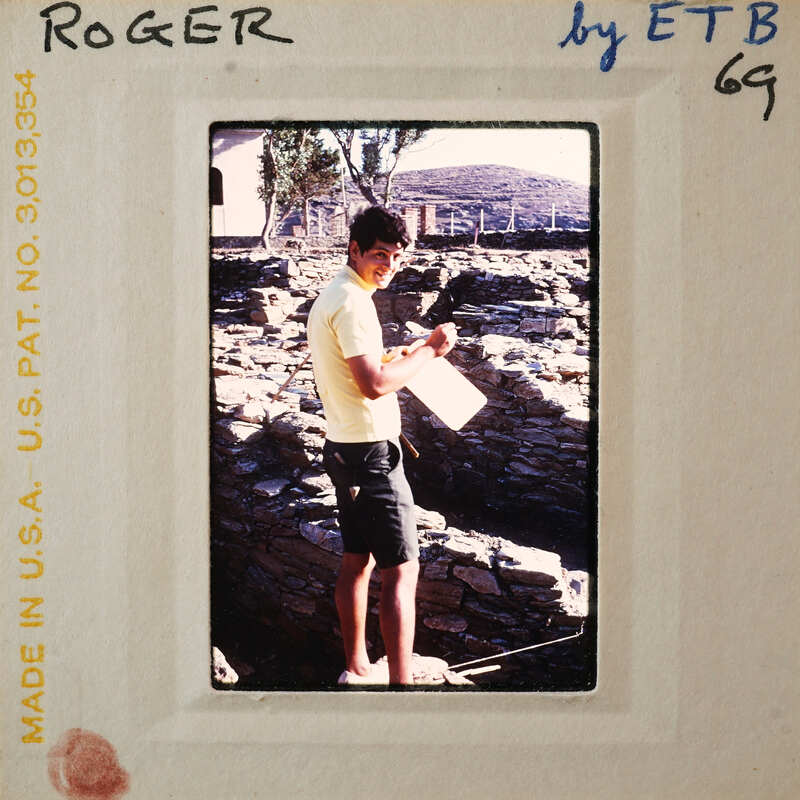 Man standing in front of a stone wall with a clipboard and pen, possibly conducting an inspection or survey.