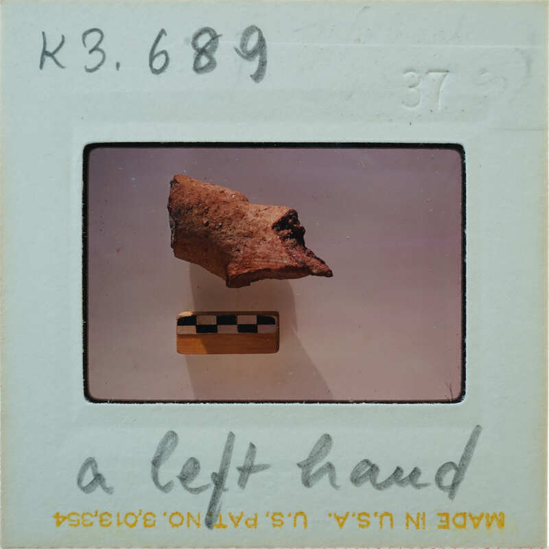 Fragment of terracotta hand on white background.