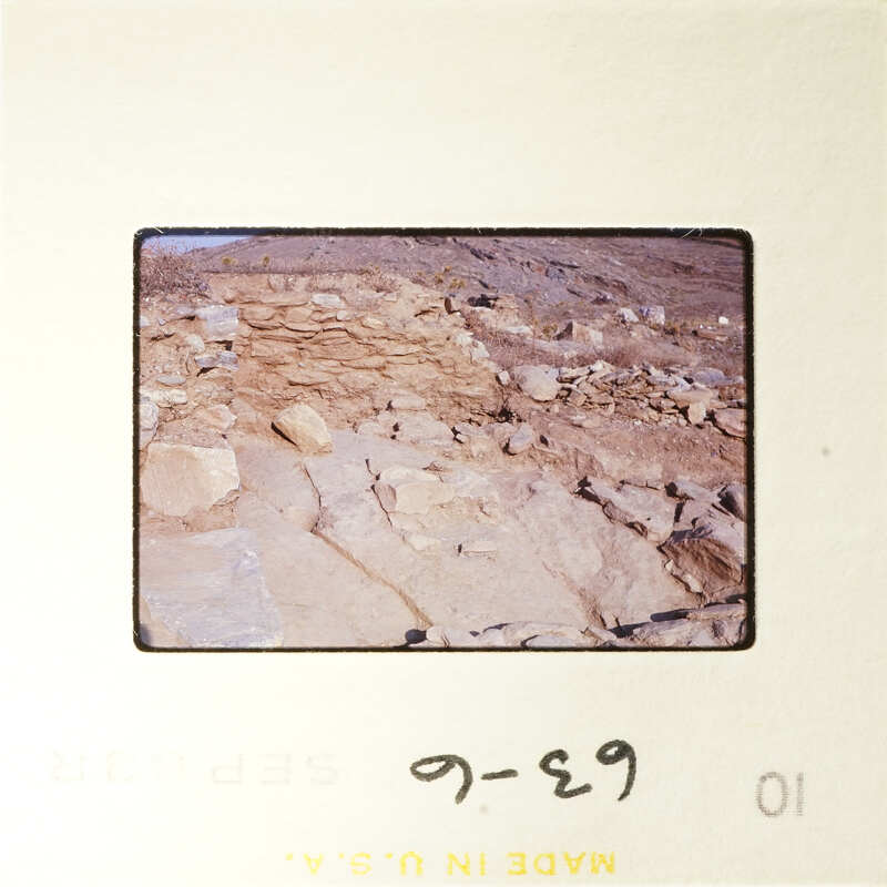 Ancient ruins with stone structures and dirt ground, photographed on film.