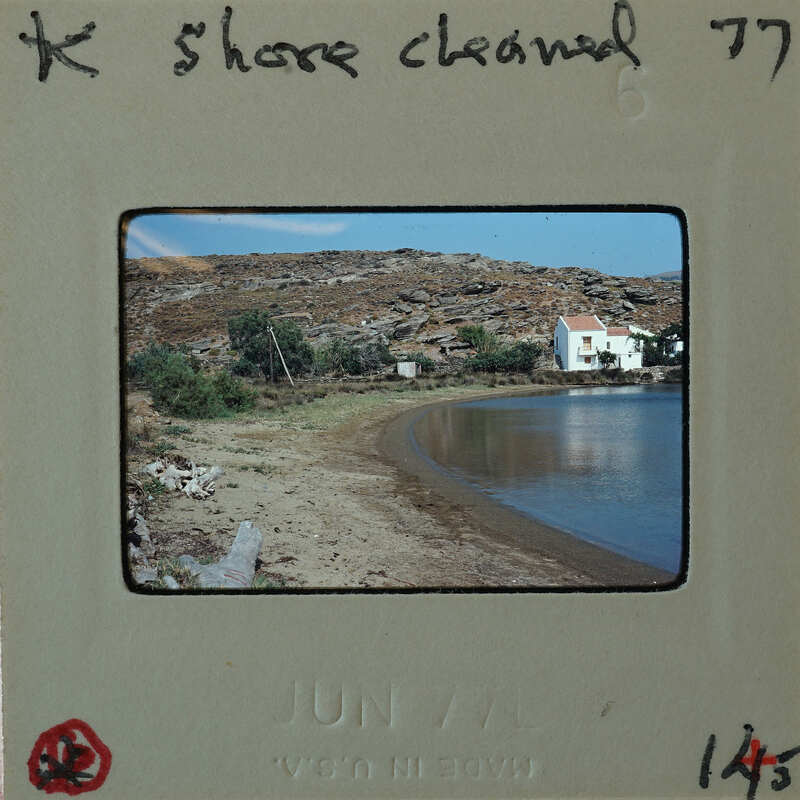 Photograph of a beach with a house and mountains.