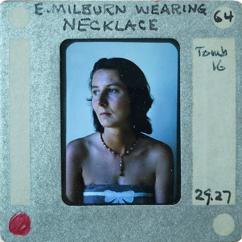 Woman wearing a necklace, with her name and details written on the slide frame.