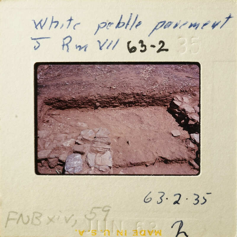 A photograph of an archaeological site with exposed layers and stones.